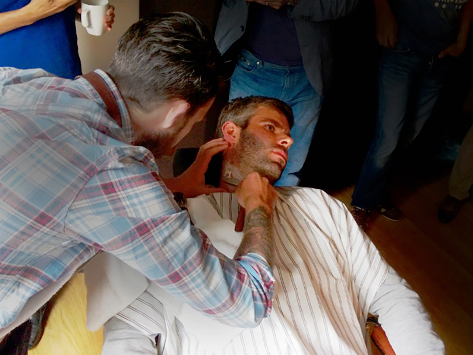 A man has his face shaved with a straight razor by a barber.