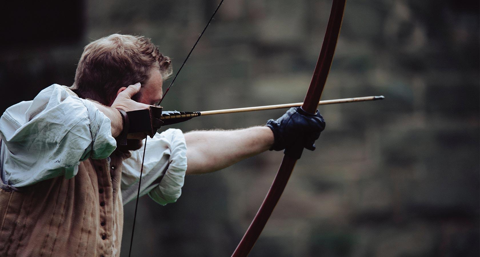Man holding a bow aiming for a specific target