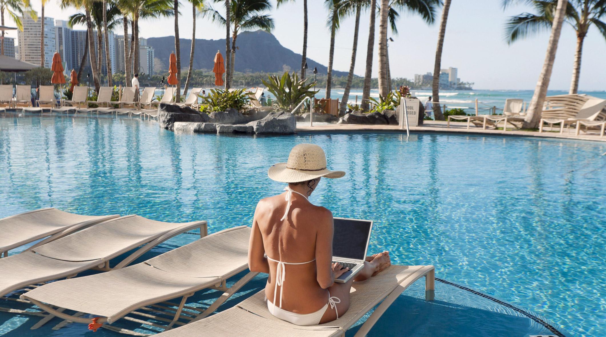 Freelance designer digital nomad remote working at a pool.
