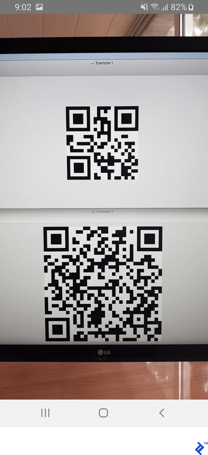 A screenshot showing a full-screen camera component. The camera is pointed at a computer monitor displaying two samples on our QR code scanner.